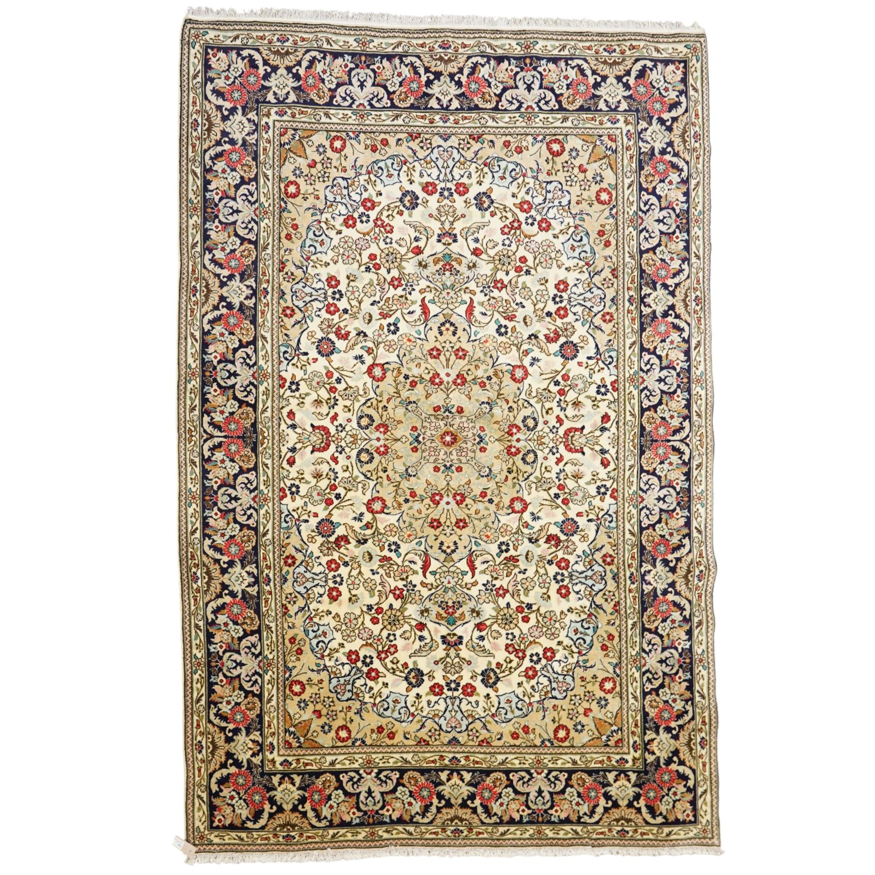 Central Persian Kashan hand-knotted carpet, ivory ground with a central floral medallion with an all-over design of scrolling vinery, palmettes, and flowering sprays i tones of madder red, cobalt, navy blue and sage green, with conforming spandrels, main border of deep indigo ground with repeating palmettes and stylized floral heads, flanked by narrow guard stripes, with cotton fringe ends, with cotton fringe ends 