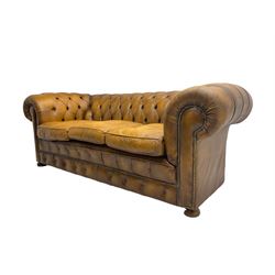 Chesterfield three seat sofa, upholstered in buttoned tan leather with studded detail, on turned feet