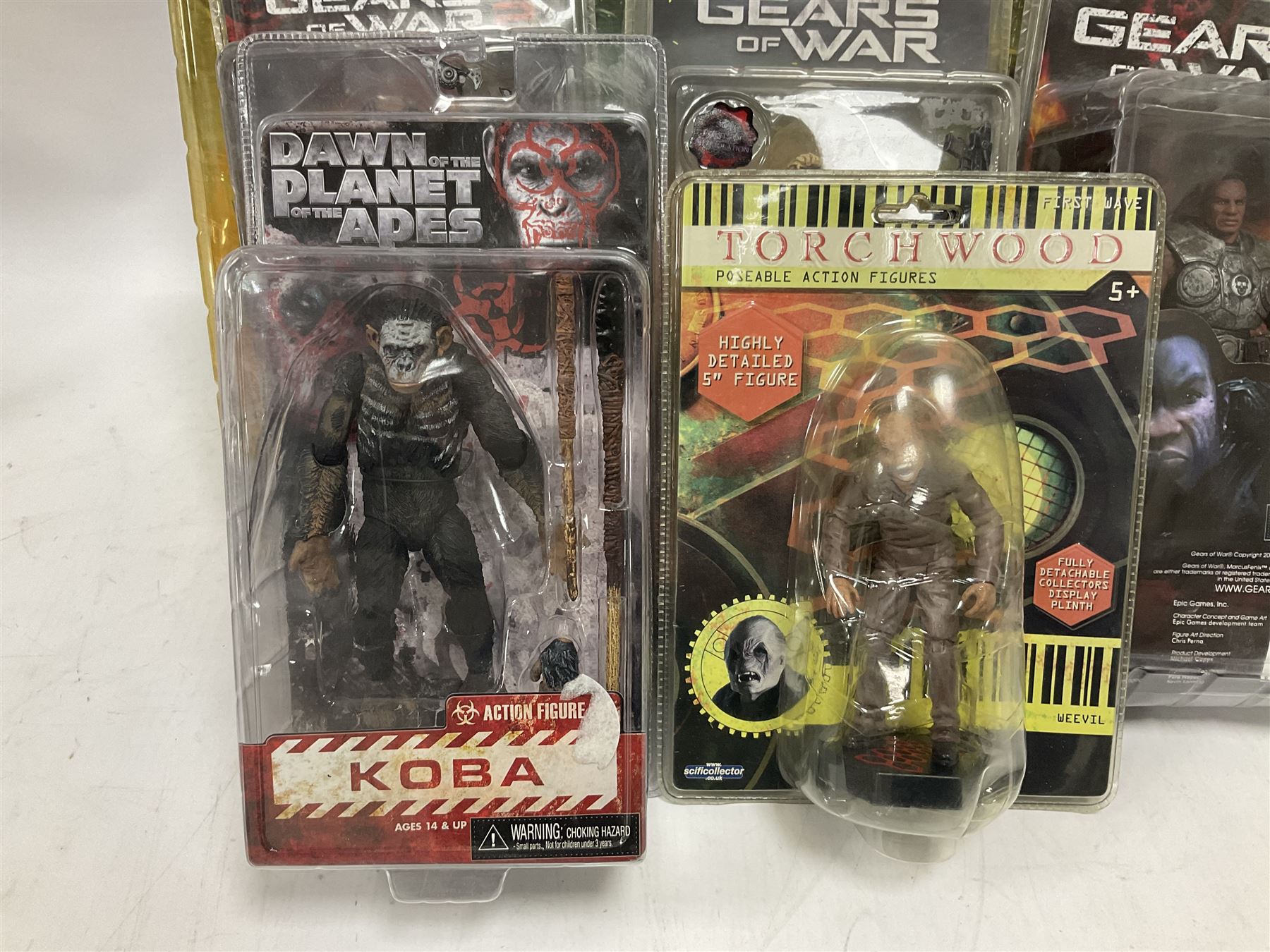 Sixteen carded action figures comprising seven 'Gears of War'; four 'Hitchhikers Guide to the Galaxy'; two 'Torchwood'; 'Planet of the Apes'; 'Bruce Lee'; and 'Assassin's Creed'; all in unopened packs (16)