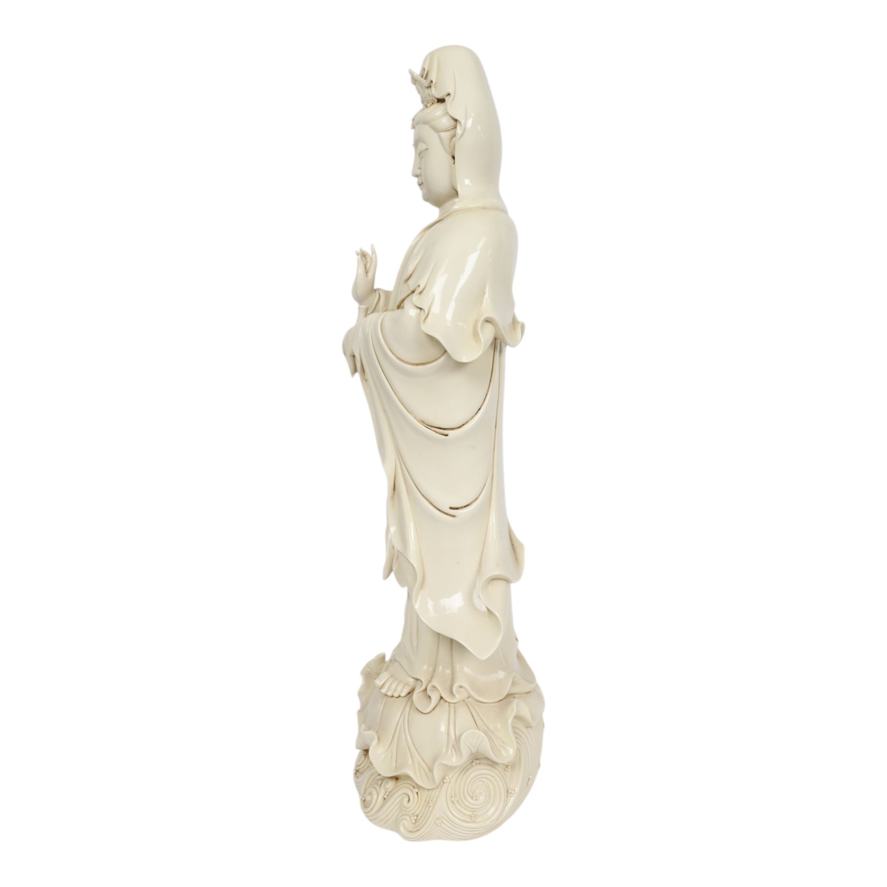 Large Chinese blanc de chine figure of Guanyin, depicting the goddess stood upon a lotus leaf with one hand raised, with potters seal mark to the reverse, H75cm