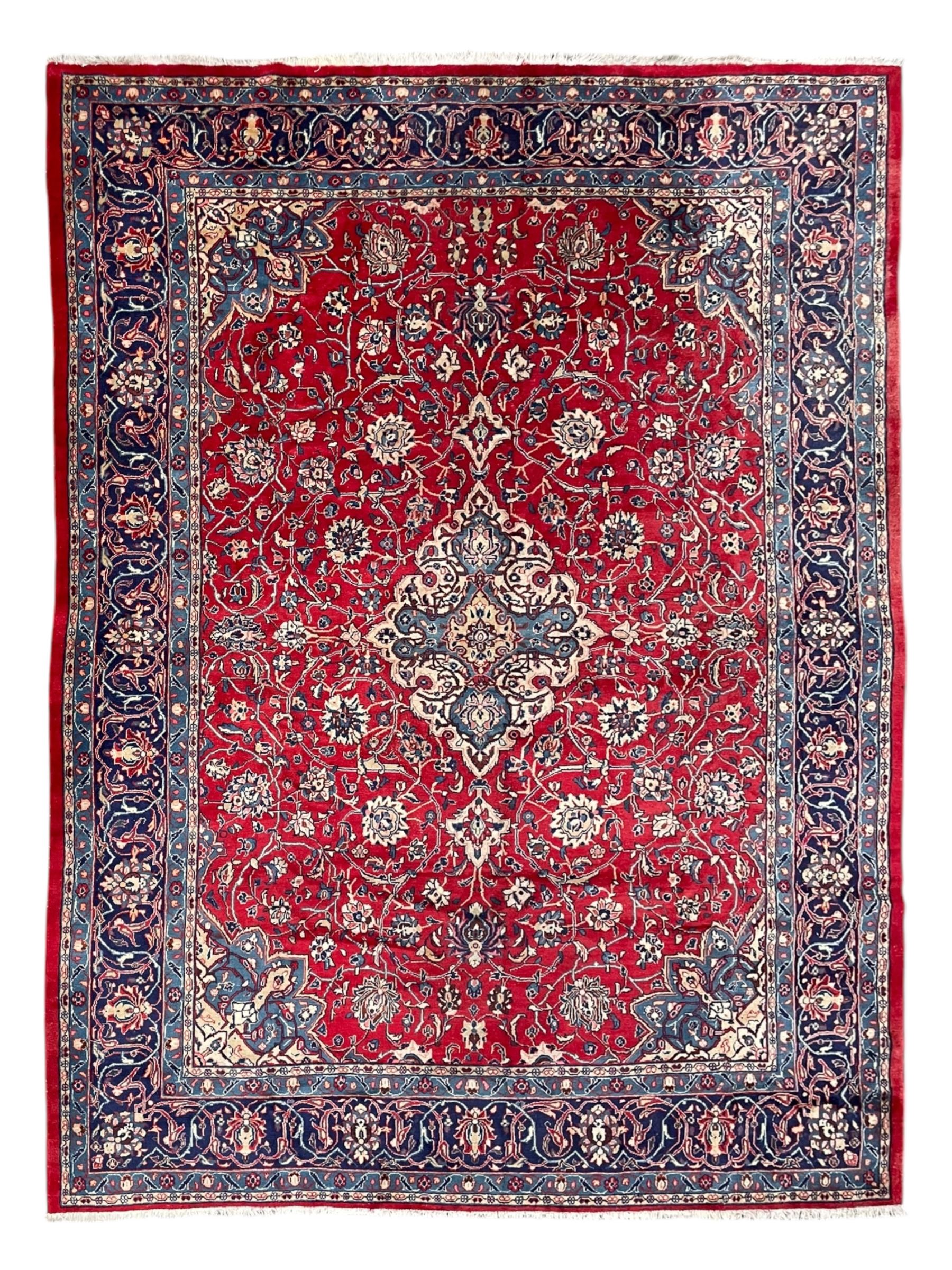 Kashan crimson ground carpet, overall floral design, the central medallion surrounded by trailing leafy branches and palmettes, scrolling border decorated with stylised plant motifs, within guard stripes