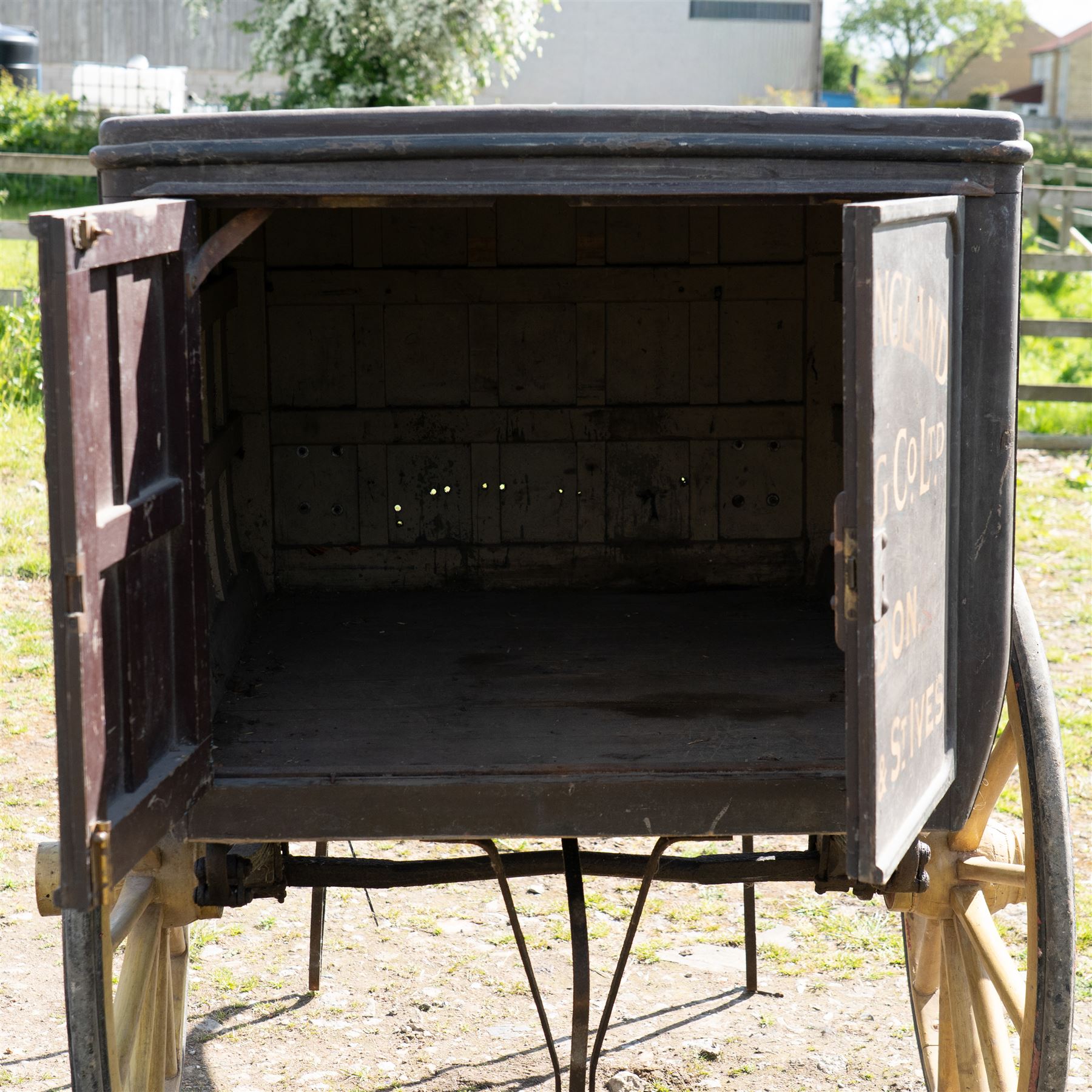 West of England Knitting Co. Ltd. Advertising Hand Cart

A rare and highly decorative late Victorian or Edwardian advertising hand cart, retaining its original black painted finish and gilt signwriting for West of England Knitting Co. Ltd., London, Penzance & St Ives. The enclosed box body is mounted on large cream painted wooden spoked wheels and fitted with rear push handles, allowing the cart to be manoeuvred by hand. Intended as a promotional and delivery vehicle for one of Britain's best known knitwear manufacturers, the cart survives as an evocative piece of commercial advertising history. The interior remains accessible via twin rear doors, while traces of the original maker's transfer for the Warwick Carrier are visible. An unusual and attractive display piece suited to collectors of advertising, transport memorabilia and social history.

Features

• Original hand painted gilt signwriting for West of England Knitting Co. Ltd.
• Advertising panels referencing London, Penzance and St Ives
• Enclosed wooden box body with twin rear access doors
• Original black painted finish with period lettering
• Large cream painted wooden spoked wheels with iron tyres
• Rear push handles for hand propelled operation
• Warwick Carrier maker's transfer remains visible
• Original undercarriage and running gear
• Attractive display piece with strong commercial advertising appeal
• Suitable for museum, retail, interior or collection display

Dimensions:
Overall length: 190 cm
Body length: 125 cm
Overall width: 140 cm
Body width: 100 cm
Height: 150 cm

Wheel Diameter:
Wheels: 92 cm