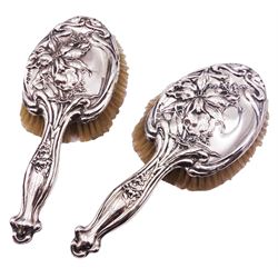 Pair of early 20th century Art Nouveau silver mounted hair brushes, decorated in relief with irises and foliate tendrils, hallmarked Samuel M Levi, Birmingham 1911