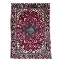 Central Persian Isfahan Carpet, hand-knotted, featuring a bold central rosette medallion on a rich red field, flanked by stylised floral sprays, scrolling foliage and mythical animals, within a broad indigo border decorated with alternating cartouches and flowerheads