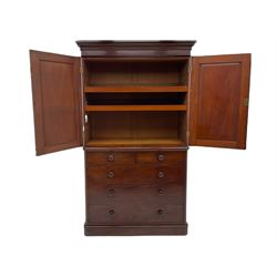Victorian mahogany linenpress, moulded projecting cornice over two arched panelled doors, the interior fitted with two linen slides, the lower section fitted with two short and three long drawers, plinth base