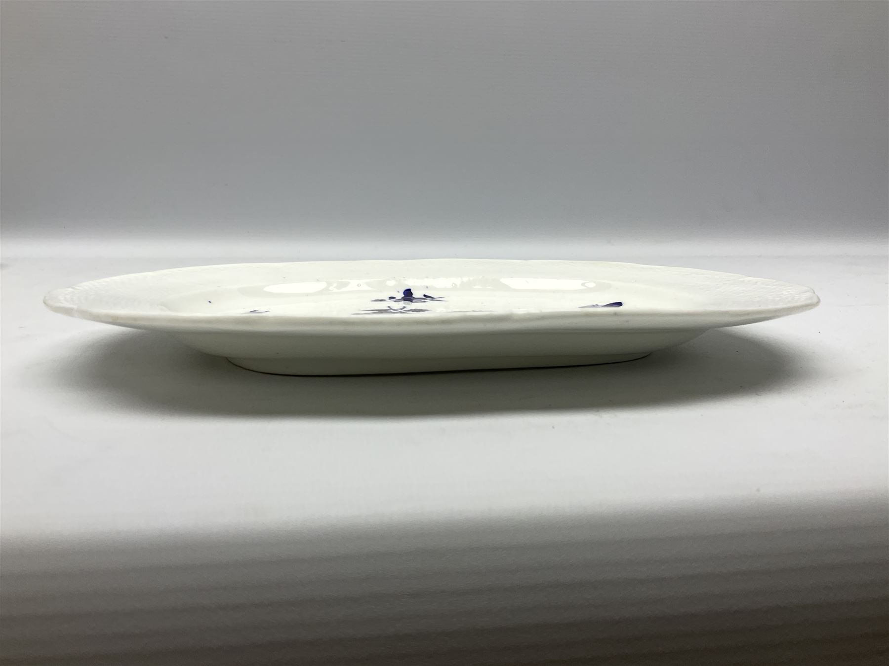 Three 19th century plates, comprising two circular examples and one oblong, each with osier moulded sides, the centres decorated in underglaze blue with Gillyflower type pattern, circular examples D25cm oblong example W27cm