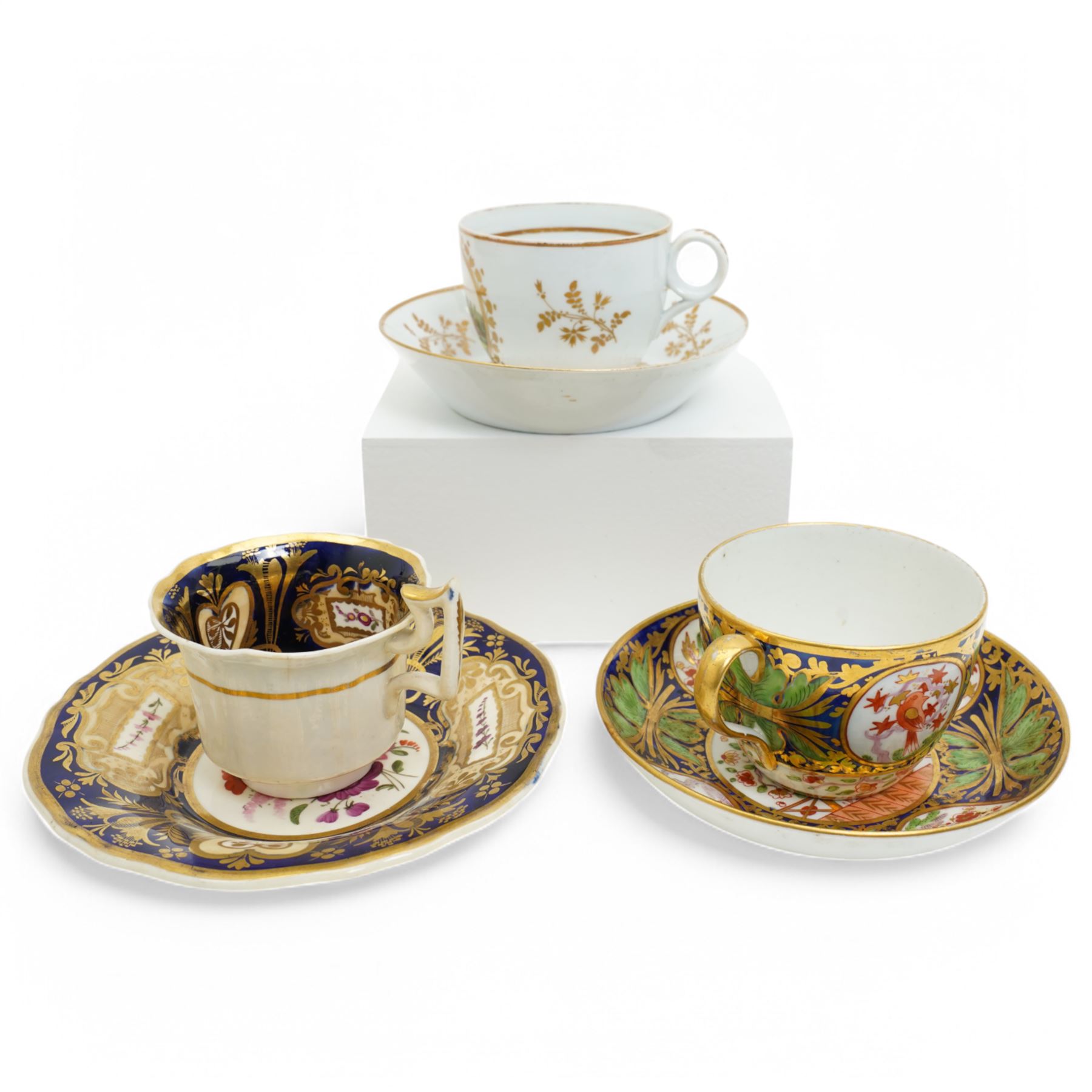19th century teacup and saucer, possibly Coalport, decorated with panels of flowers on a cobalt blue ground with gilt decoration; together with two other teacup and saucer pairs, one with hand painted landscape decoration 