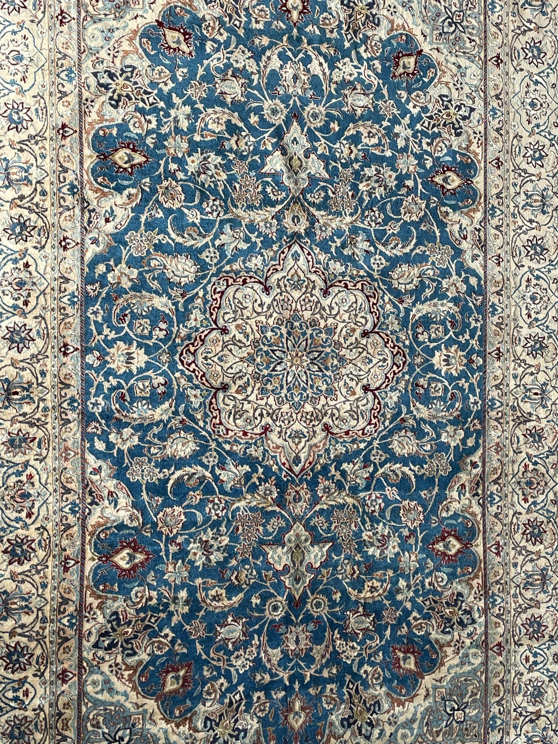 Persian Nain blue and ivory ground rug, wool with silk inlay, overall arabesque design, central medallion surrounded by interlacing and scrolled leafy branches and palmettes, the scrolling border decorated with stylised plant motifs, within guard stripes