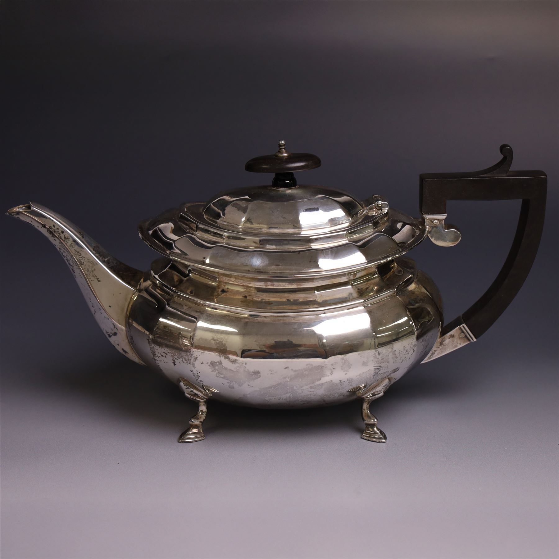 Early 20th century silver four piece tea service, comprising hot water pot, teapot, open sucrier and milk jug, each of part fluted oval form upon four stepped feet, the teapot and hot water pot with ebonised handle and finial, hallmarked Stephenson & Law, Sheffield 1918