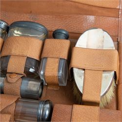 1920s gentleman's travelling case by Mappin & Webb Ltd, tan leather impressed with initials NAO, opening to reveal a compartmentalised interior containing silver mounted dressing table items, including a pair of silver mounted brushes, engraved NAO AMA 1918, hallmarked William Comyns, London 1911, five faceted glass jars and bottles with silver lids and a silver shaving brush holder, all hallmarked Mappin & Webb Ltd, London 1922, tan leather box containing razor, silver plated shoe horn, scissors and bevelled edge shaving mirror with easel support
