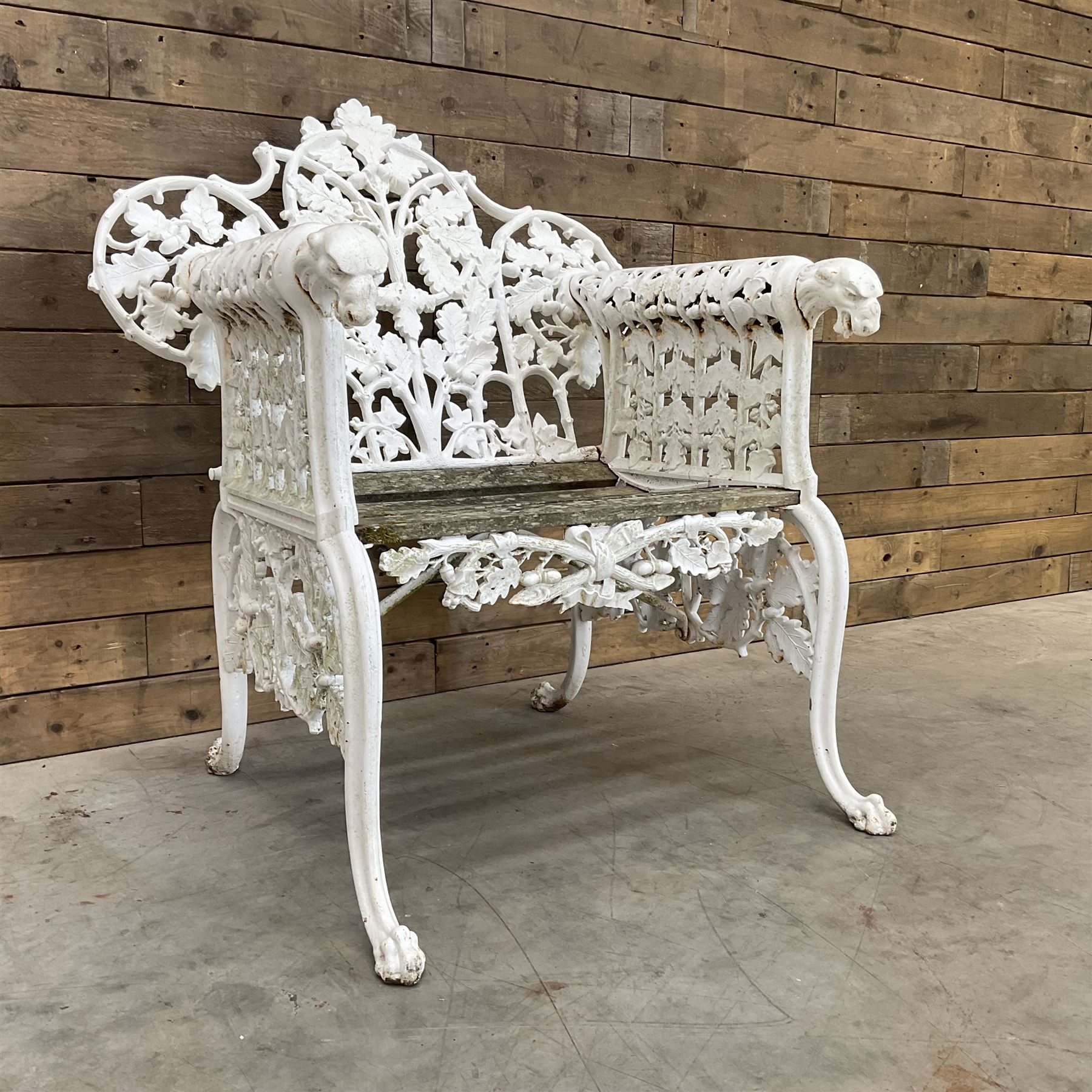 20th century Coalbrookdale design cast iron oak leaf and acorn armchair, white painted cast iron frame with slatted wooden seat, the pierced and shaped back decorated with scrolling oak branches and leafage, flanked by dog mask arm terminals over cabriole supports with paw feet