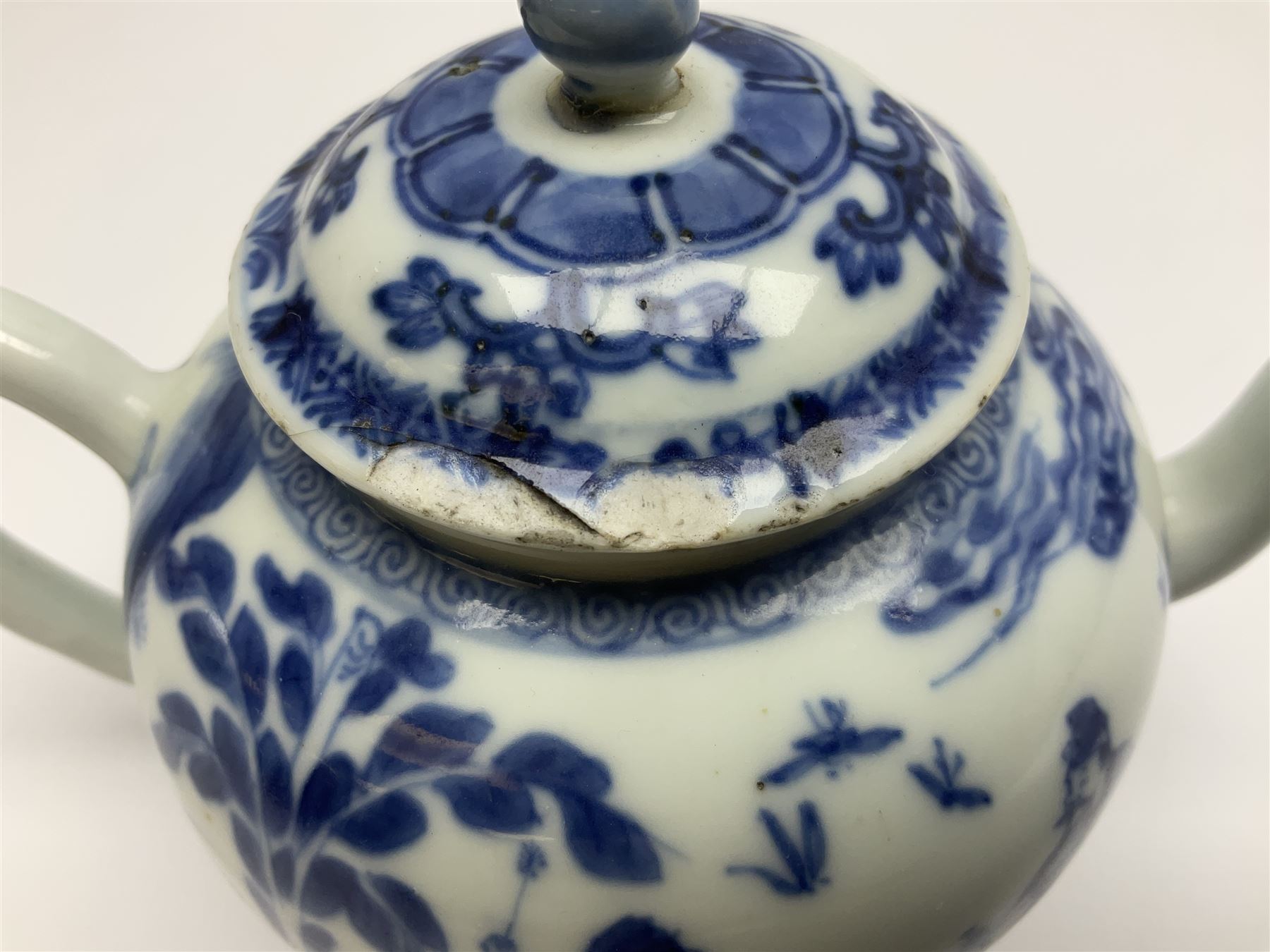 Two late 18th/early 19th century Chinese export teapots, the largest example of globular form with curved handle and straight spout, decorated in the Mandarin style with figural scenes surrounded by red scale reserves, H13.5cm, the second smaller example decorated in underglaze blue with two musicians in a landscape set with willow tree and fence, H10.5cm

