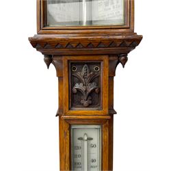 J Hicks - Hatton Garden London, - late 19th century carved oak cased Fitzroy barometer in a richly carved case with a carved crested pediment and square cistern cover, inverted opaline register reflecting FitzRoy's predictions and a scale from 27 to 31 inches of barometric pressure, with a thick bore cistern tube and adjustable rack and pinion twin vernier, fitted with a glazed snail bulb mercury thermometer recording the air temperature in both Fahrenheit and Celsius. Mercury clean and present.
James Joseph Hicks was born in Ireland, however, early in his life he moved to London where he was apprenticed to the instrument maker Louis P Casella. In 1860 he went into business in his own right as a scientific instrument maker at 8 Hatton Gardens. In 1864 he was granted membership to the British Meteorological Society and exhibited instruments at the Royal Society Exhibitions between 1876 and 1913. Hicks was one of London's most prolific and eminent barometer makers. 