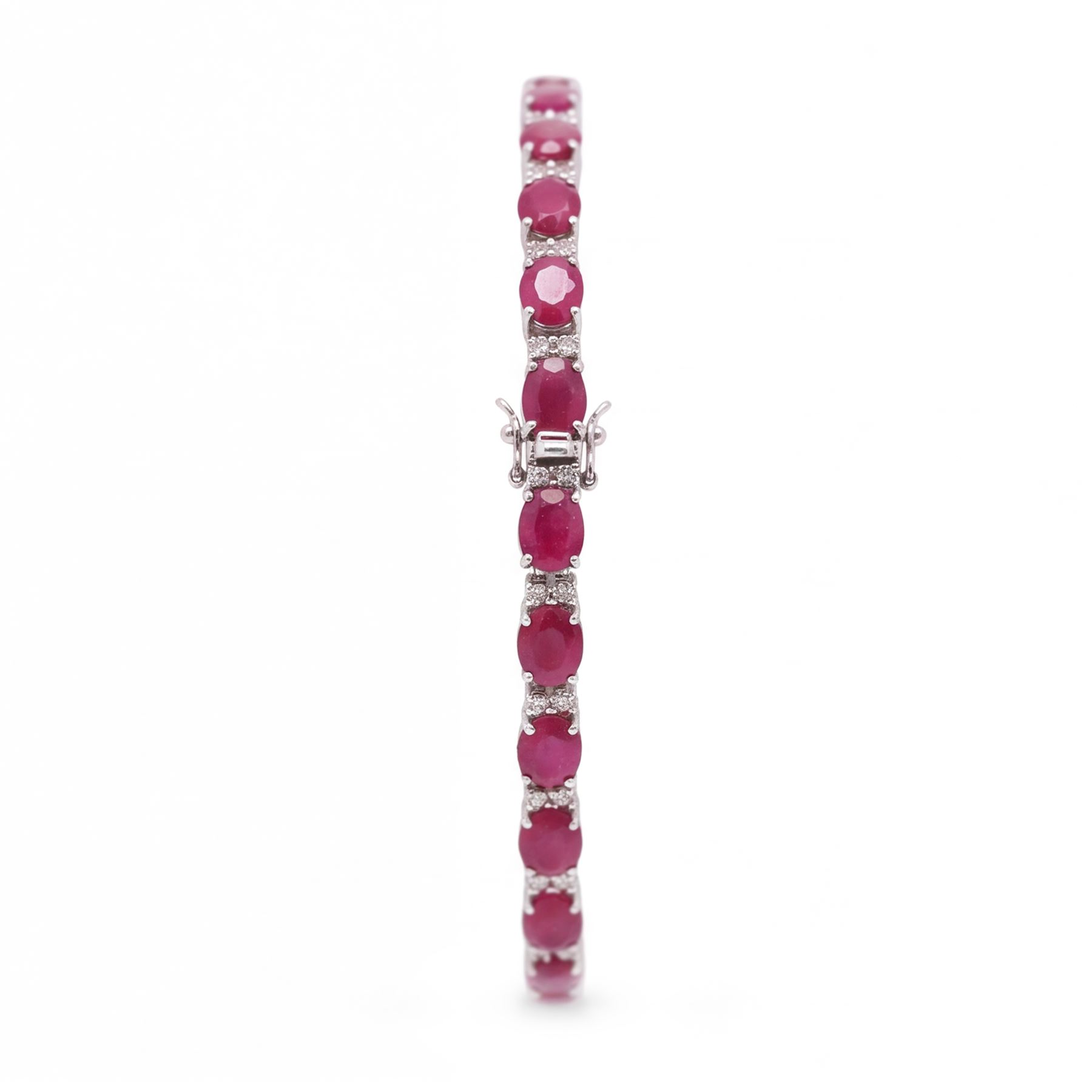 18ct white gold ruby and diamond bracelet, twenty-six oval cut rubies, each spaced by two round brilliant cut diamonds, stamped 750, total ruby weight 12.70 carat, total diamond weight 0.46 carat