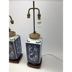 A pair of blue and white table lamps, of square sectional form decorated with dragons, prunus blossom, bats and a key fret border, each upon wooden base, overall H66cm. 