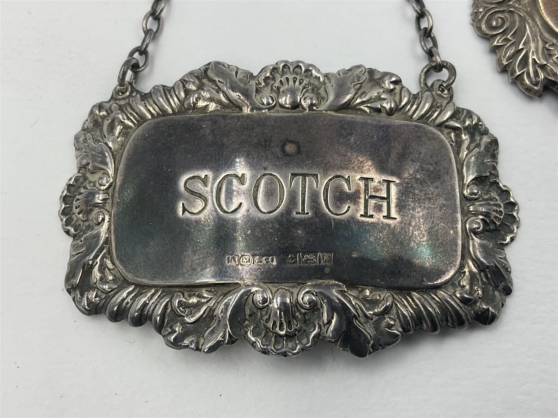 Five modern silver decanter labels, to include three similar Sherry and Brandy examples embossed with scrolls, two hallmarked C Robathan & Son, Birmingham 1989, and one hallmarked Laurence R Watson & Co, Birmingham 1987, together with a scotch example, hallmarked A Marston & Co, Birmingham 1970, and a larger sherry example, embossed with fruiting vines, hallmarked A Marston & Co, Birmingham 1993