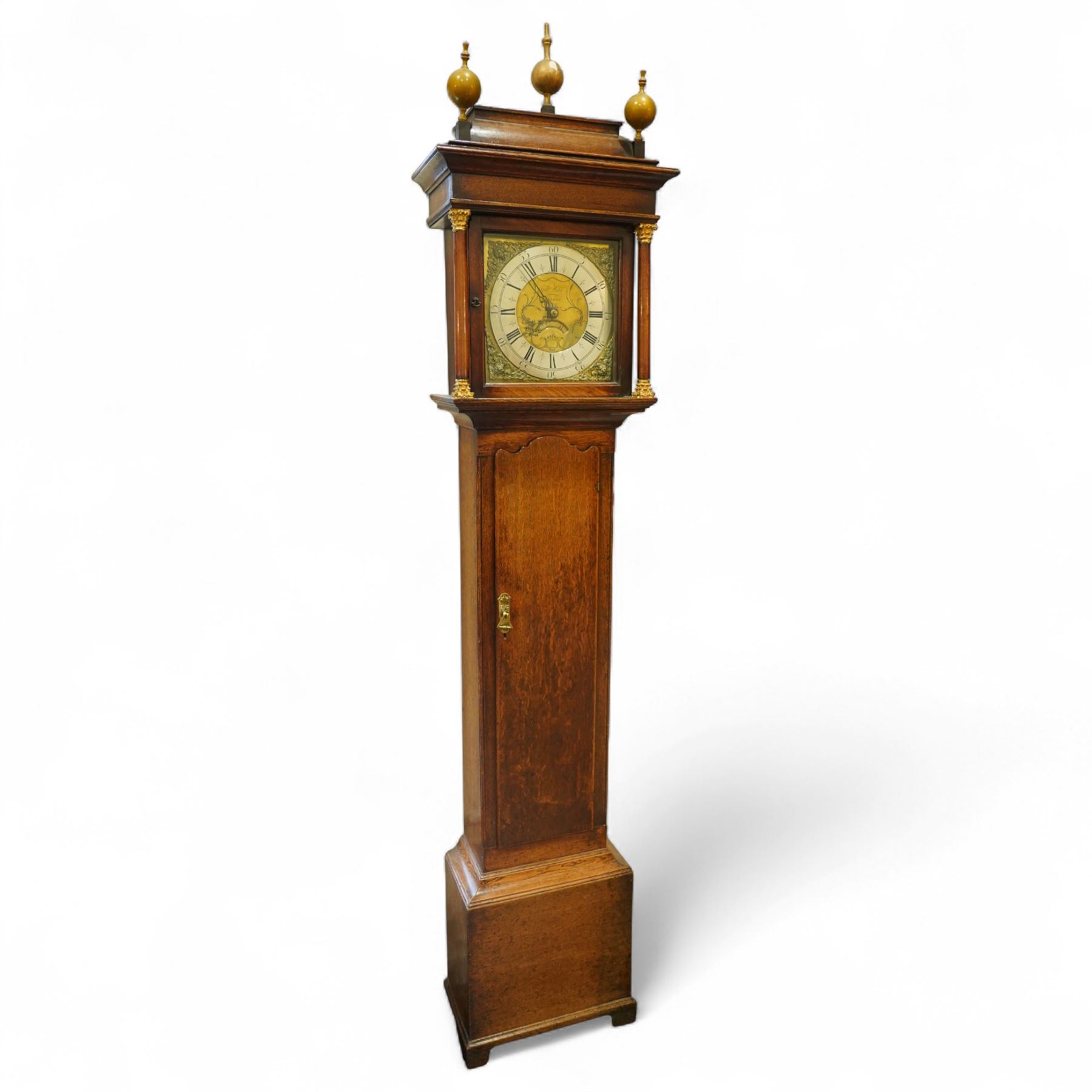 Gilbert Kidd of Malton-oak cased mid-18th century 30hr longcase clock, with a caddy top and three gesso finials, square hood door flanked by turned pilasters with Corinthian capitals, trunk with a long wavy topped door on a square plinth with an shaped skirt, brass dial with an engraved dial centre, date aperture and steal hands, silvered chapter ring with Roman numerals and five minute Arabic's, dial pinned to a chain driven countwheel striking movement. With a brass cased weight and pendulum. 