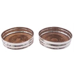 Pair of modern silver mounted bottle coasters, each of circular form with turned mahogany base, hallmarked London 1981 and 1982, makers mark AP, D13cm