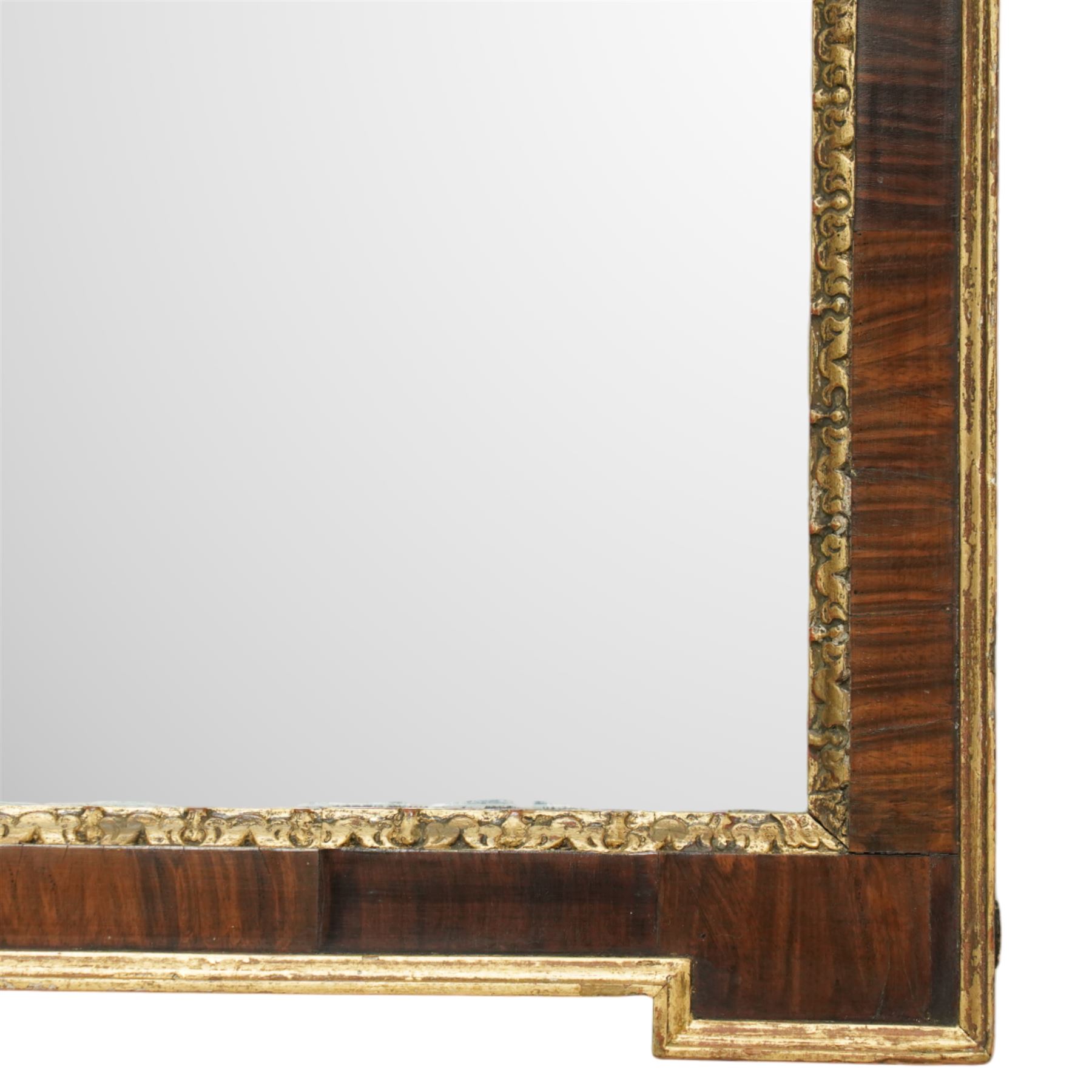 George I style mahogany and gesso architectural style wall mirror, with rectangular mirror plate bordered by gilt foliate moulded slip, within a shaped and crossbanded mahogany frame with stepped corner