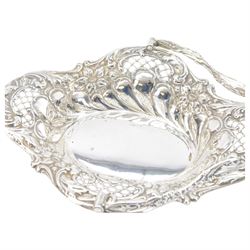 Edwardian silver swing handled basket, of oval form with shaped rim, embossed with floral decoration and with pierced latticework sides, upon four pad feet, hallmarked Chester 1905, maker's mark worn and indistinct