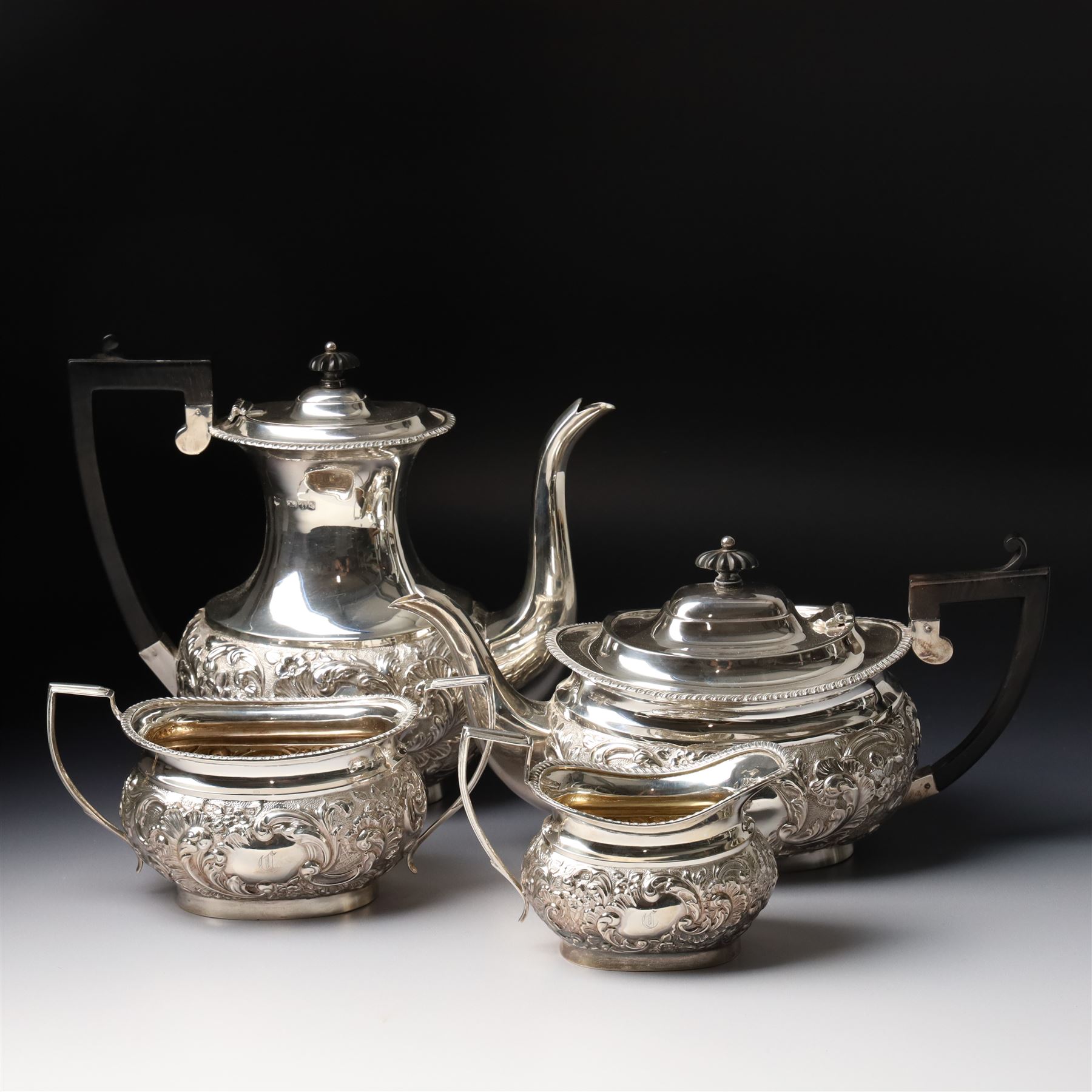 Late Victorian four piece silver tea set comprising teapot, coffee pot, sugar bowl and milk jug with embossed decoration, the cartouches engraved with an initial, the teapot and coffee pot Chester 1899 Maker George Nathan & Ridley Hayes, the sugar bowl and milk jug Birmingham 1899 Maker Thomas Hayes