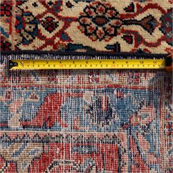 Large West Persian Bidjar hand-knotted carpet, deep indigo field with central medallion with pendants issuing an all-over design of scrolling vines, palmettes, and floral sprays, within conforming spandrels, enclosed a broad madder red palmette, and vine border framed by guard stripes, in a palette, of indigo, madder red and ivory tones, with cotton fringe ends 