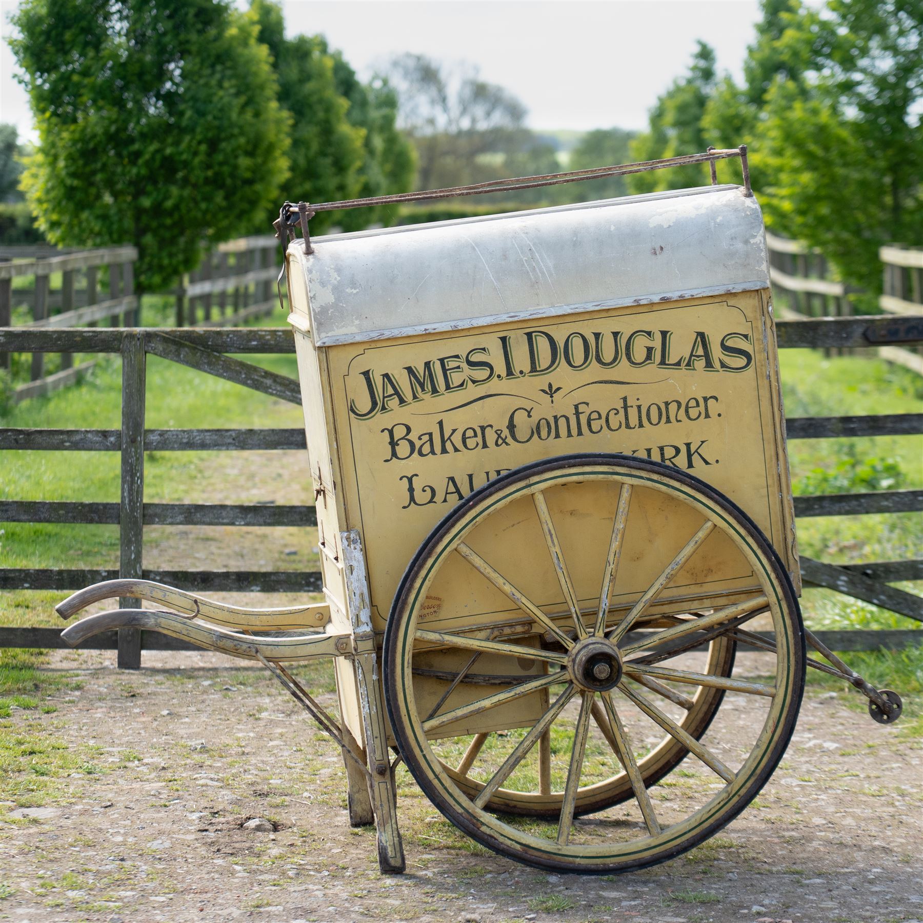 James I. Douglas, Baker & Confectioner, Laurencekirk Hand Drawn Delivery Cart

An attractive late 19th or early 20th century hand drawn baker's delivery cart, finished in cream and retaining its original hand painted advertising livery for James I. Douglas, Baker & Confectioner, Laurencekirk. The enclosed body features a curved roof with external luggage rail, rear access doors and internal shelving for the transport and delivery of bread, cakes and confectionery. Mounted on large wooden spoked wheels with iron tyres and fitted with shaped shafts for a single horse, this is a highly decorative and increasingly scarce example of a provincial tradesman's delivery vehicle, offering excellent display potential for collectors, museums, period interiors or commercial settings.

Features:
• Original hand painted signwriting for James I. Douglas, Baker & Confectioner, Laurencekirk
• Enclosed delivery body with curved roof and external luggage rail
• Rear opening access doors with internal storage compartments
• Original internal wooden shelving and racks
• Large wooden spoked wheels with iron tyres
• Shaped shafts for single horse traction
• Builder's mark for Geo. Roberson Ltd., Wallington
• Decorative cream painted finish with period lining and detailing
• Suitable as a display piece, museum exhibit or advertising feature

Dimensions:
Overall length: 170 cm
Body length: 104 cm
Width: 83 cm
Height: 150 cm

Wheel Diameter:
Wheels: 95 cm