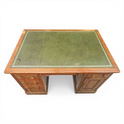 20th century oak compact pedestal desk, tooled green leather inset top, above a single frieze drawer, with a bank of four graduated drawers and a drawer and cupboard, panelled sides raised on castors