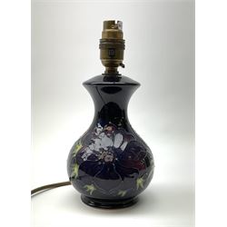A Moorcroft table lamp, of baluster form, decorated in the Anemone pattern upon a dark blue ground, with impressed marks beneath, with accompanying cream shade with piped detail, overall H38.5cm.