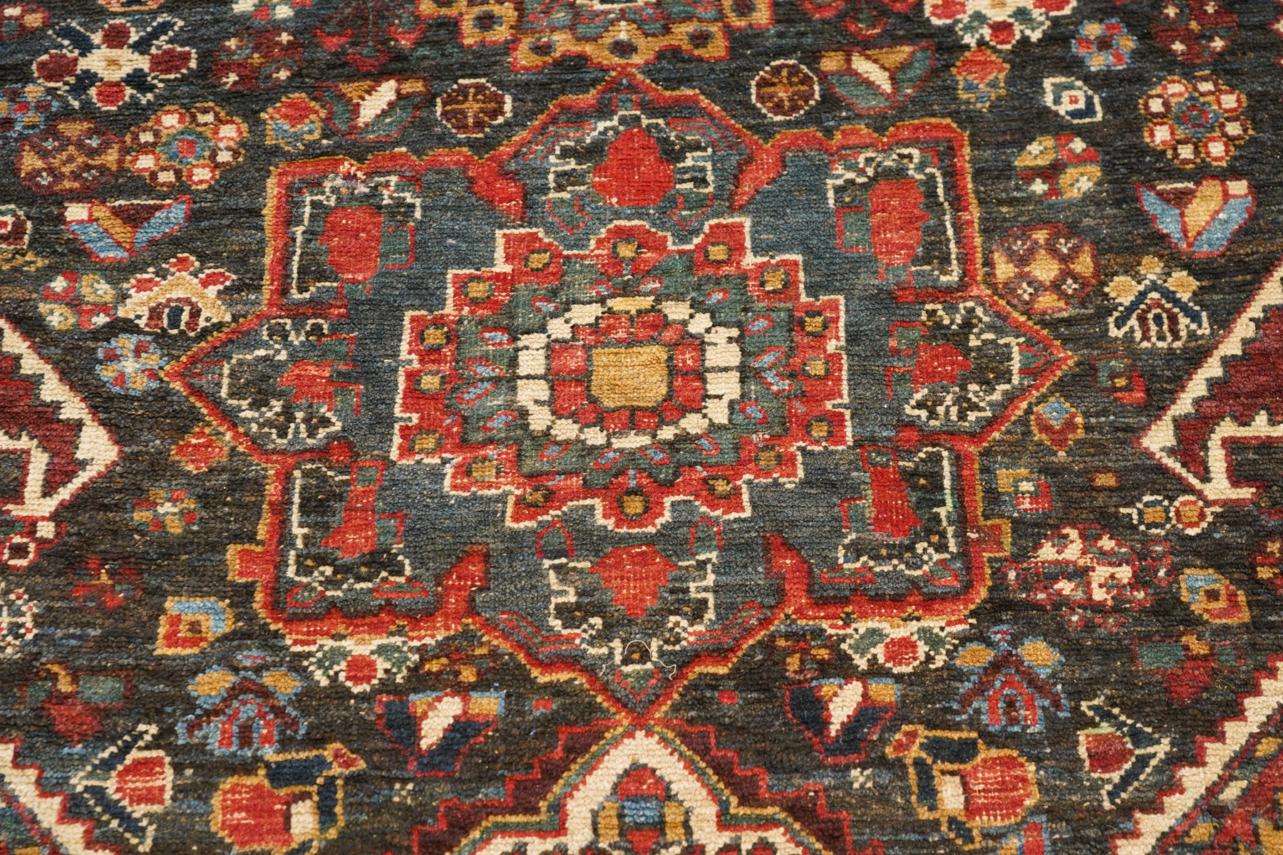 Antique Persian Qashqai dark indigo ground tribal rug, the busy field decorated with a geometric triple pole medallion surrounded by numerous stylised plant motifs with contrasting cyan spandrels, the multiple guard bands woven with stylised palmettes and foliage