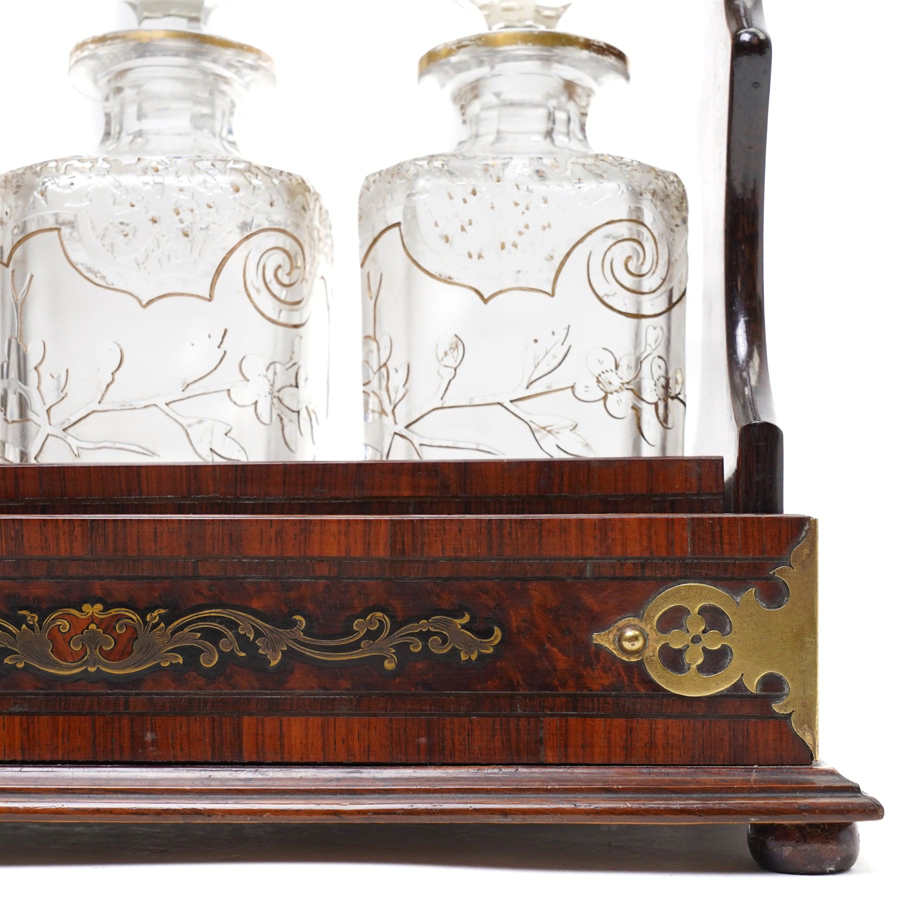 Amboyna three bottle tantalus, the cut glass spirit decanters decorated with raised naturalistic decoration heightened in gilt, with brass corner mounts and singular carrying handle, H32cm