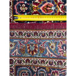 Central Persian Kashan hand-knotted carpet, madder red field with an intricate design of scrolling vines, palmettes, and rosettes with a central lobbed medallion with pendant motifs in shades of blue and ivory, and spandrels all within a blue-ground border of palmettes and flowerheads between multiple guard borders, 450cm x 335cm 