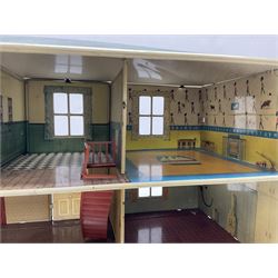 Mid-20th century Mettoy tin-plate double-fronted two-storey doll's house, the front elevation with five unglazed windows flanked by green shutters, central opening door, open back giving access to five rooms together with an attached garage, 60cm wide