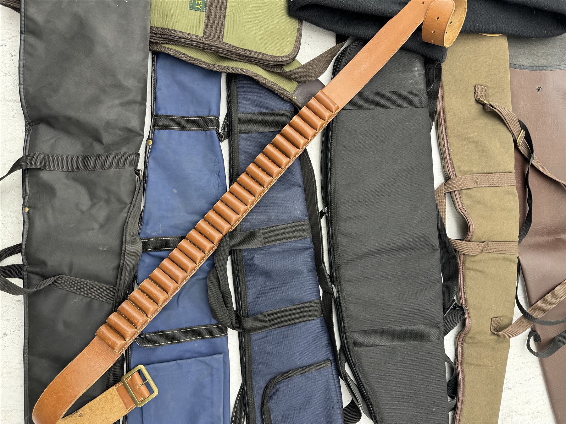 Collection of gun slips, including BSA guns and napier examples and leather 12-bore cartridge belt 