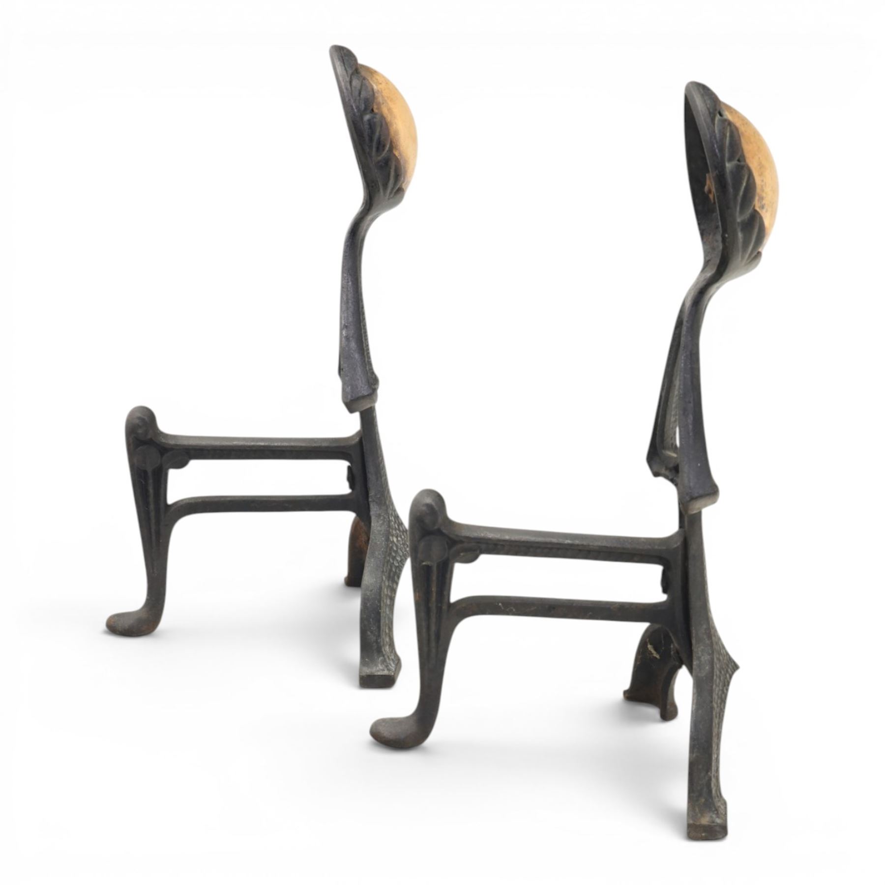 Arts and Crafts cast iron and brass andirons, brass and copper acorn finials above openwork uprights, raised on shaped arched feet with hammered detail