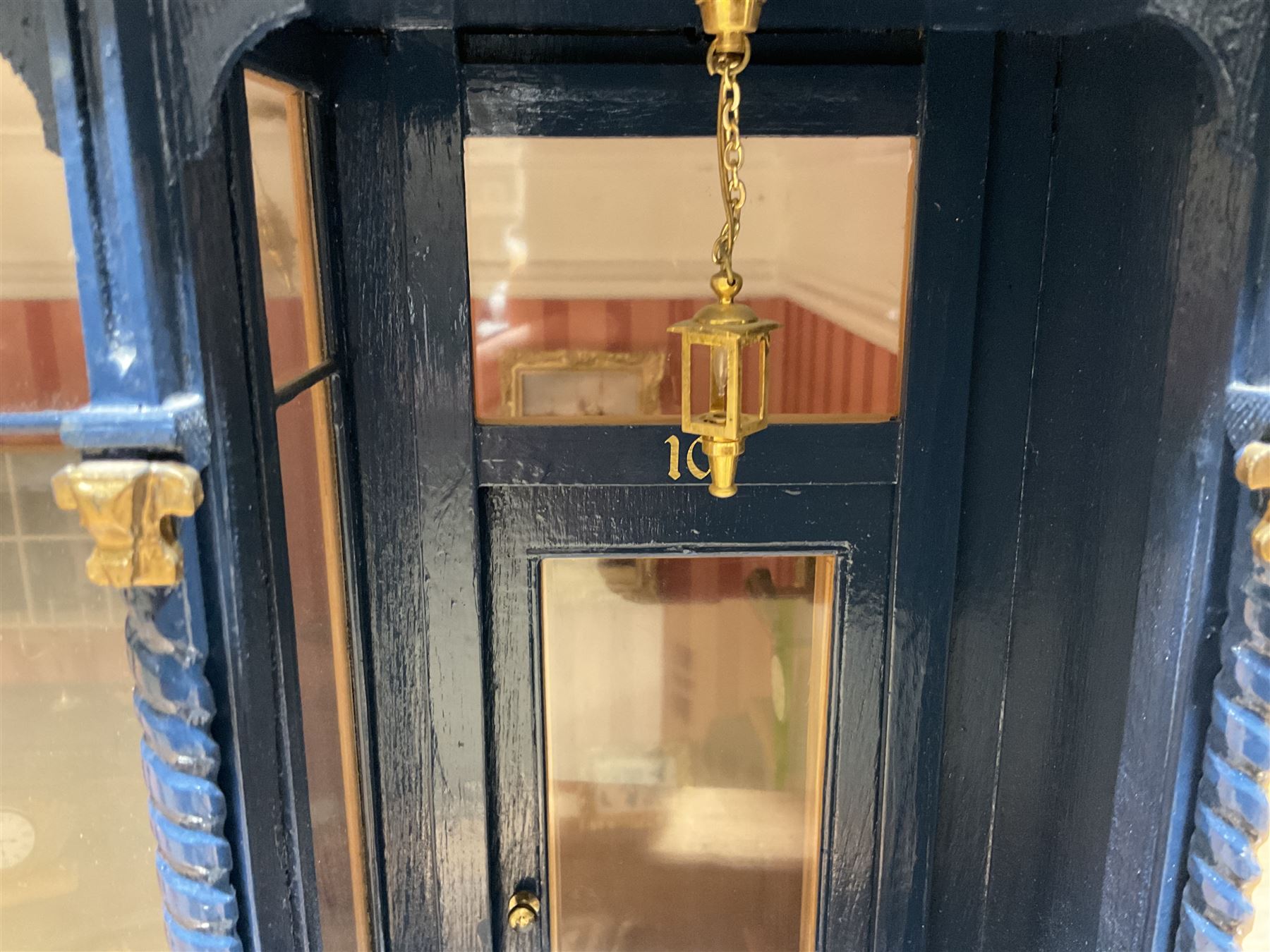 Good quality late 20th century dolls house by M. James dated 1995 in the form of a Beverley East Yorkshire Antique Shop called 'North Bar Antiques'; single-storey single-roomed shop with textured brick walls and flat roof, fully glazed hinged front with recessed hinged customer door and central window to the rear; comprehensively furnished with chests of drawers, pedestal desk, breakfast table, lowboy, two longcase clocks, delft rack with ceramics, occasional tables, pictures, Regency style mirror and collectibles; decorated walls with coving and picture rail and simulated floorboarding; wired for electric lighting; maker's plaque W61cm H42.5cm D41.5cm