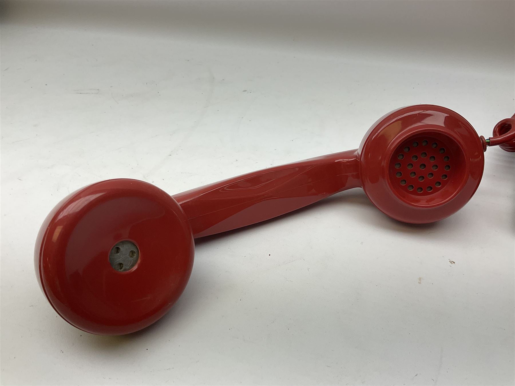 Two mid 19th century red telephones with rotary dials, comprising example marked G.P.O Batch Sampled 8532 706L AEG 67/2A, with junction box marked G.P.O, and another with chrome dial marked P.O Authorised Release 21034 746F EET 78/2