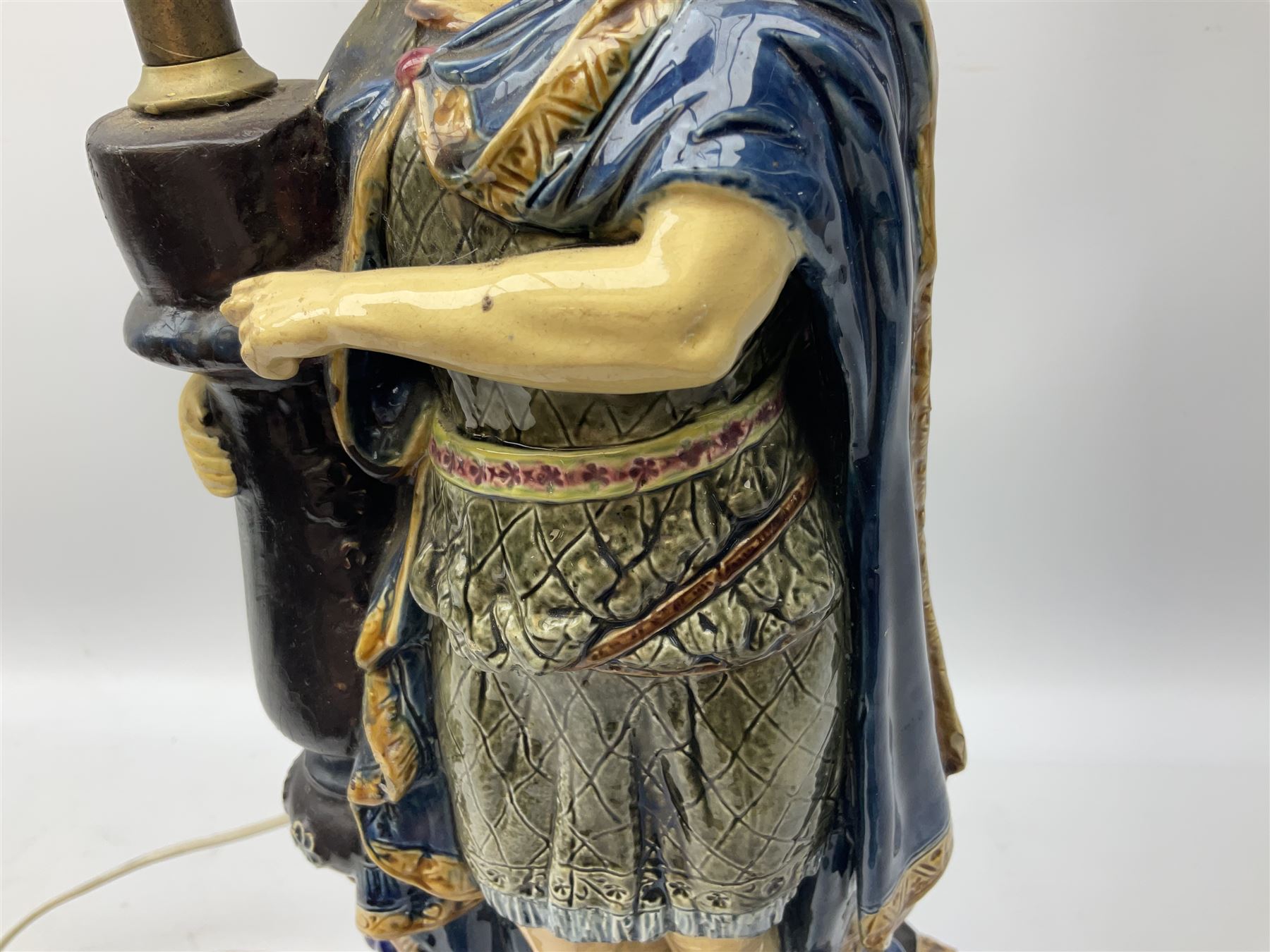 Composite table lamp modelled as a Roman Emperor donning blue robes, upon quatrefoil base modelled with rams heads and winged cherubs, H56cm excl fitting