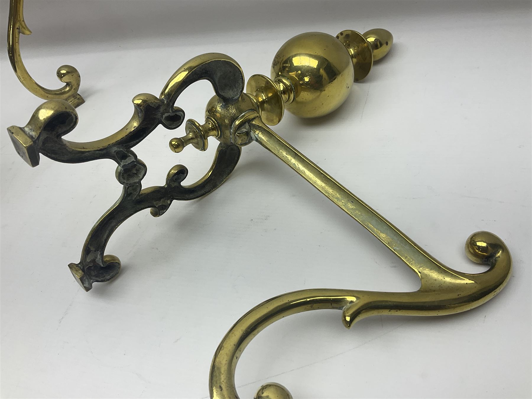 Pair of early 20th century brass fire dogs, each with sphere and urn finial, upon a scrolling base, H38cm