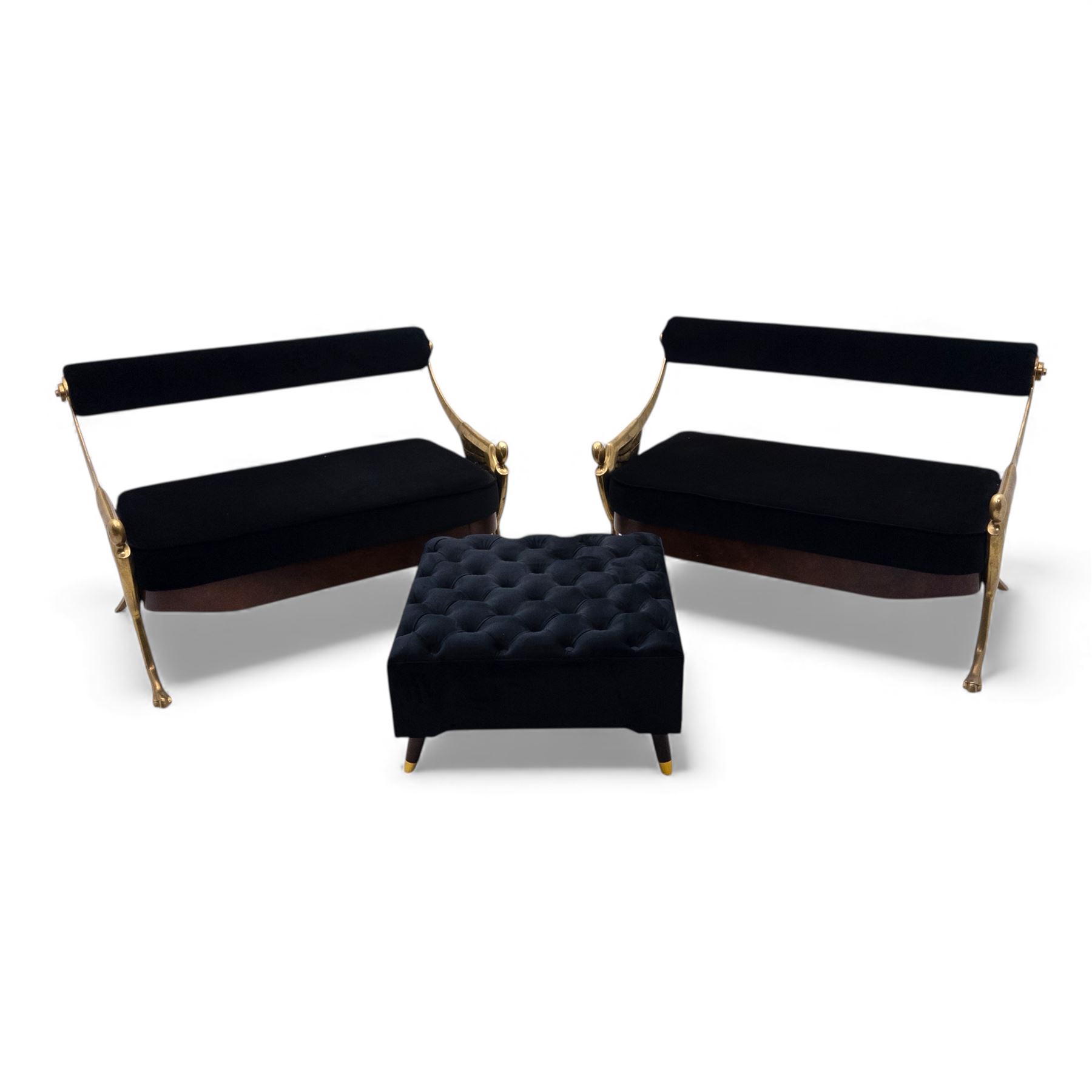 Late 20th century pair of Empire inspired brass metal framed two-seater sofas, upholstered in black velvet with cylindrical backrest and sphinx form arms terminating in paw feet, together with matching deep buttoned black velvet footstool on brass capped legs (Footstool H 38cm, W 70cm, D 70cm)