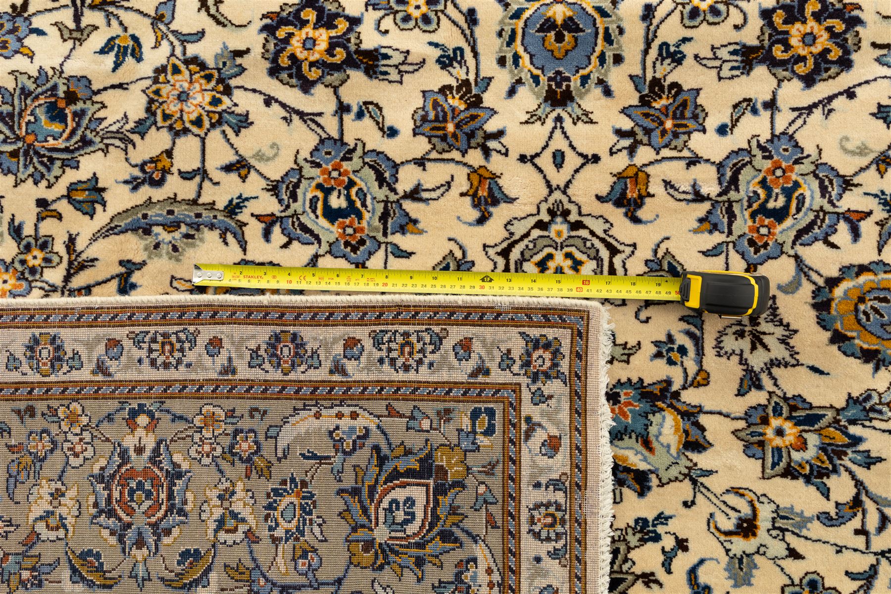 Central Persian Kashan hand-knotted rug, ivory field intricately decorated with an all-over design of scrolling vines, palmettes, and stylized lotus motifs in shades of soft blue, pale gold, and indigo within floral borders