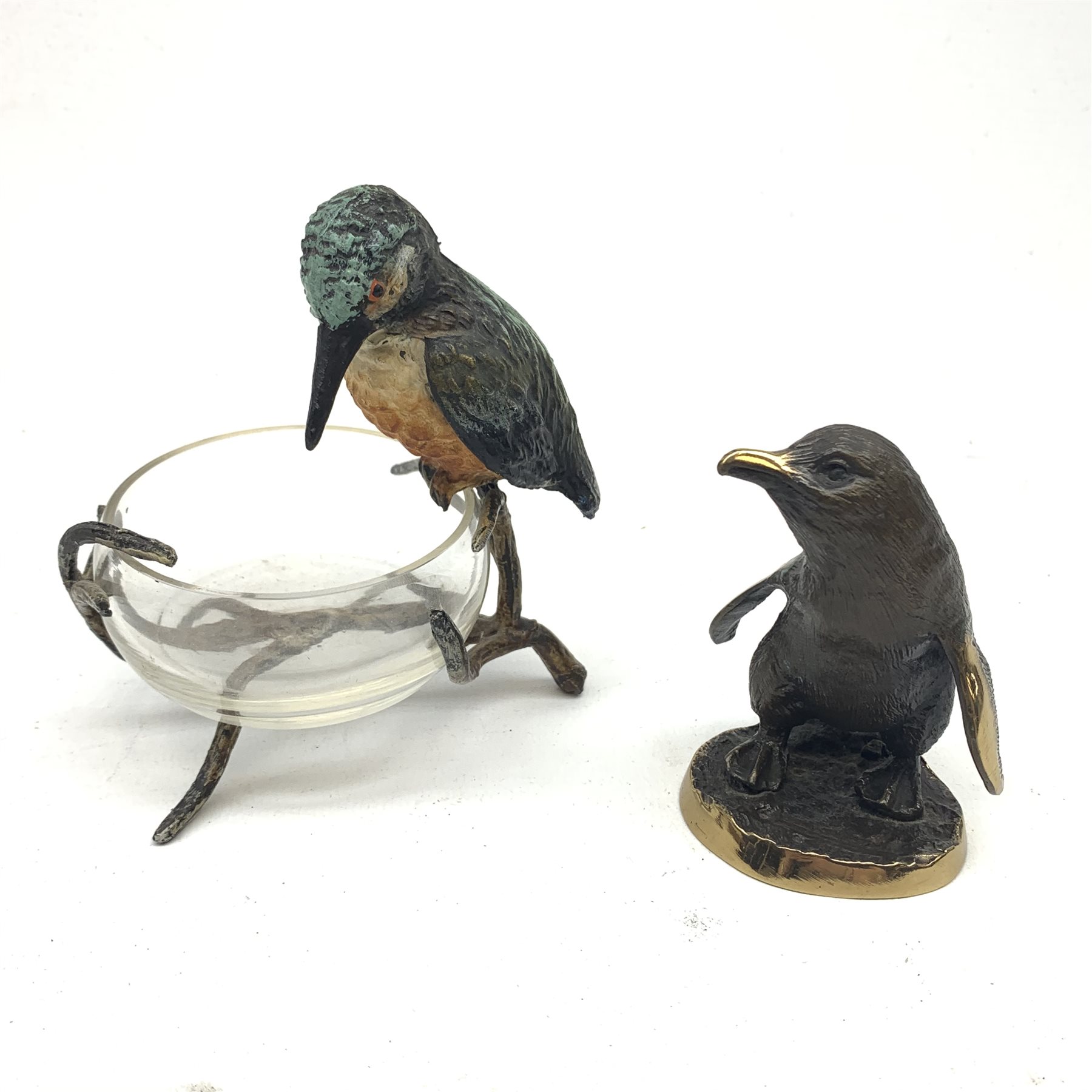 A cold painted model of a Kingfisher surmounted upon a branch surporting a small clear glass bowl, H10.5cm, together with a small bronze model of a penguin, stamped EWB, H7cm. 