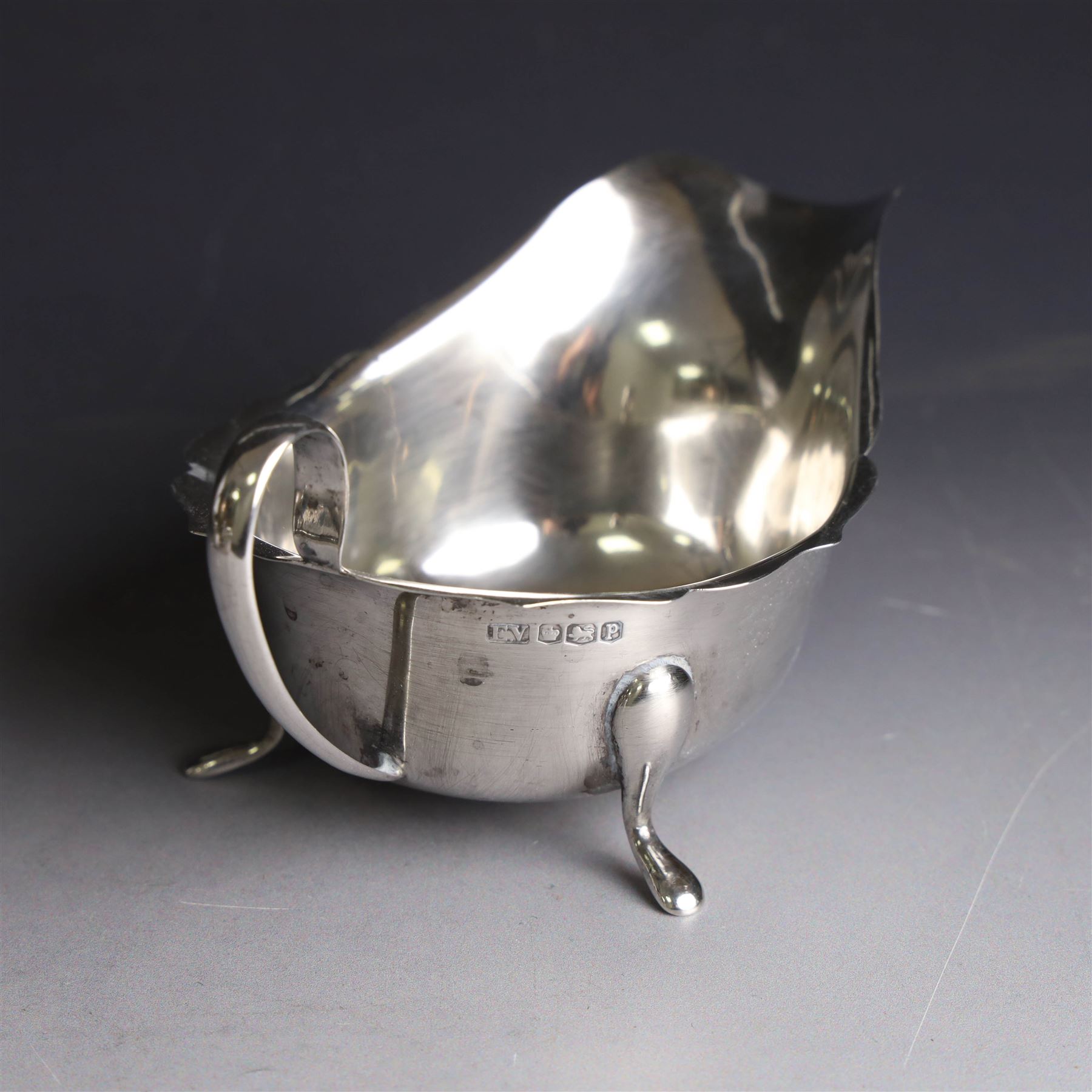 Three silver sauce boats, comprising pair of 1930s silver sauce boats, of typical form with shaped rim, scroll handle and upon three pad feet, hallmarked Viner's Ltd, Sheffield 1932 and a similar 1920s example with flying C scroll handle and upon three paw feet, hallmarked James Deakin & Sons, Sheffield 1923, tallest including handle H7.5cm