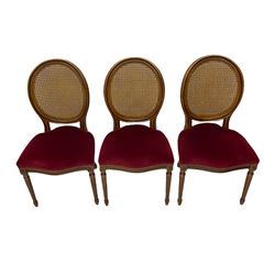 Set six French style walnut finish dining chairs, oval cane bergere backs over serpentine seats upholstered in red, flower head carved fluted supports