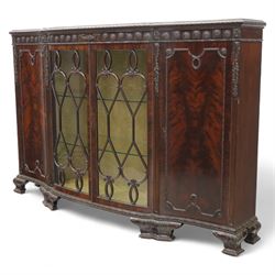 Edwardian mahogany serpentine breakfront display cabinet in the neoclassical style, the rectangular top above a carved frieze with roundels, foliage, and ribbon tied swags with central bow-fronted astragal glazed doors enclosing shelves, flanked by panelled doors, raised on bracket feet 
