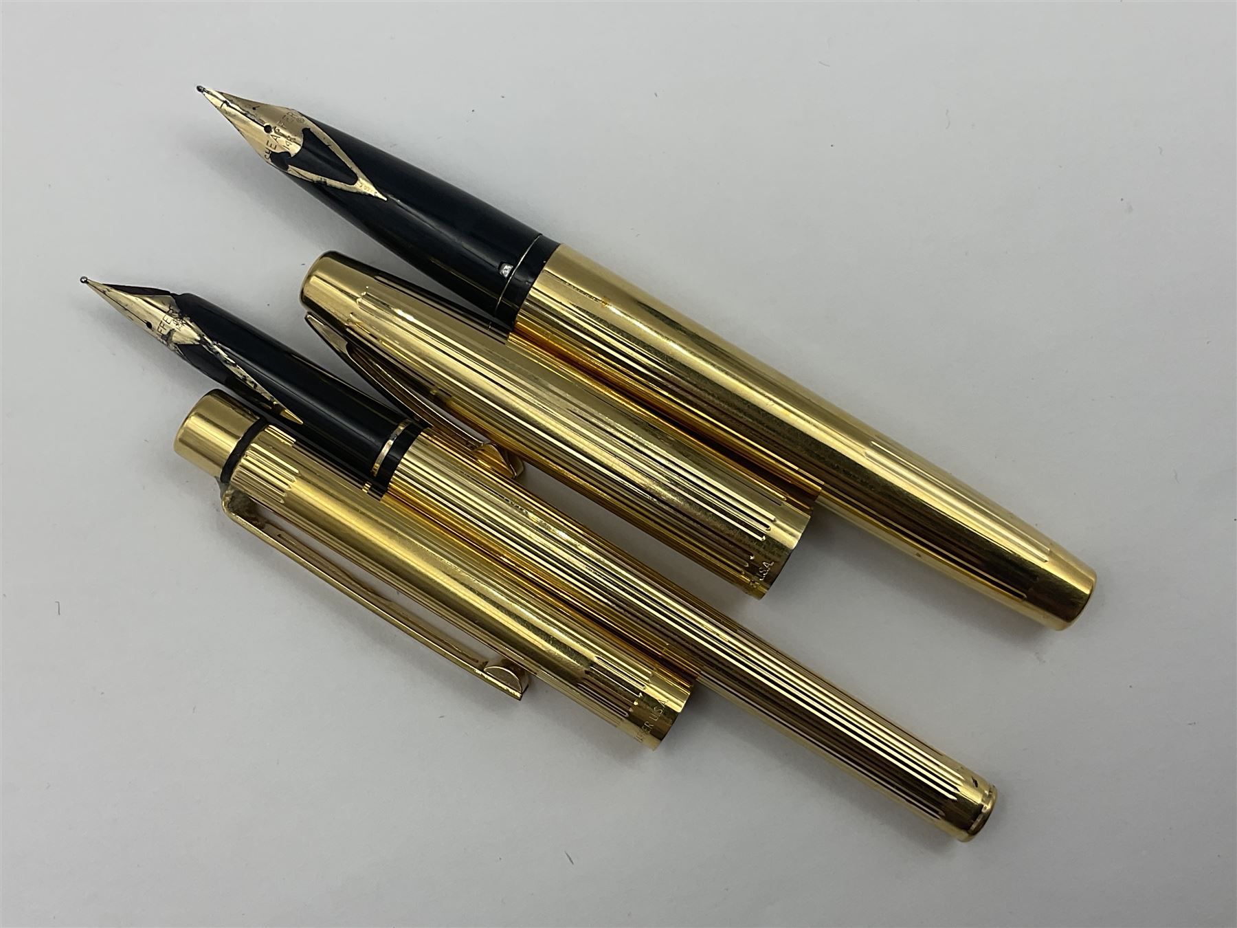 Sheaffer Triumph Imperial fountain pen, the gold plated barrel with fluted stripe design and gold nib stamped 14K 585, together with a Sheaffer Targa slimline fountain pen with gold plated barrel similarly decorated with gold nib stamped 14K 585, ballpoint pen and propelling pencil, each with a fluted gold plated barrel, largest L13.5cm (4)