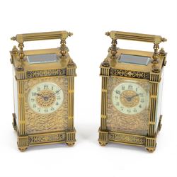 French - Matching pair of Edwardian 8-day timepiece carriage clocks with bevelled rectangular glass panels and overlaid friezes in gilt repousse work with fretted dial masks,  circular enamel chapter ring with Arabic numerals and steel spade hands, both clocks with single train movements, one movement with a jewelled cylinder platform escapement and the other with a jewelled and silvered lever platform escapement.
No Keys.