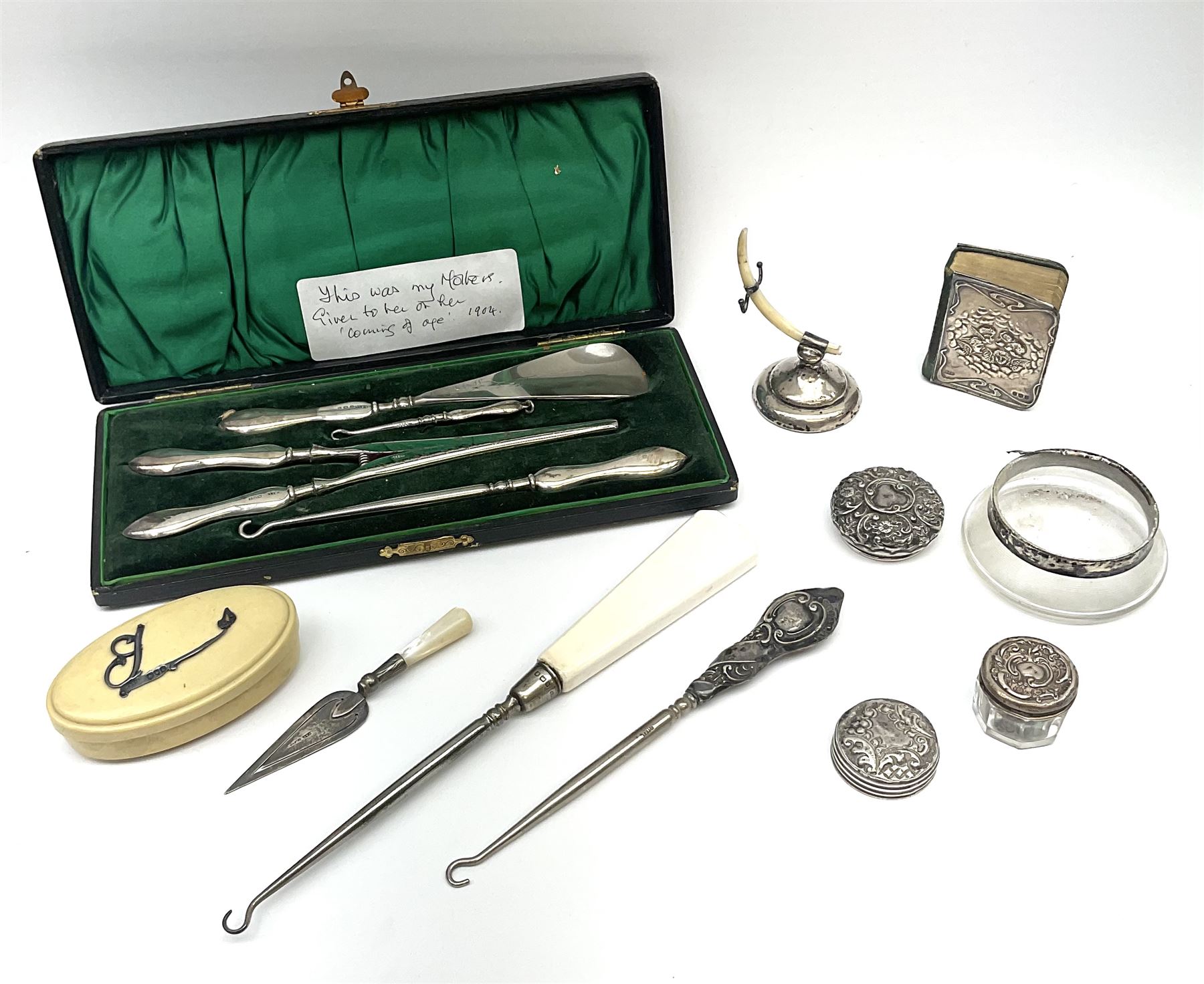 Cased silver handled glove stretcher, button hook, shoe horn, etc., hallmarked Adie & Lovekin Ltd, Chester 1911, and Adie & Lovekin Ltd, Birmingham 1911, miniature silver mounted hymn book, the cover embossed with cherubs, silver handled button hook, ivory handled button hook with silver ferrule, two silver dressing table pot lids, etc. 