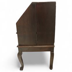 Early 18th century George I oak bureau on original stand, the fall front enclosing an arrangement of correspondence drawers and pigeonholes over central well, fitted with single long drawer below, the shaped apron over cabriole supports with pad feet