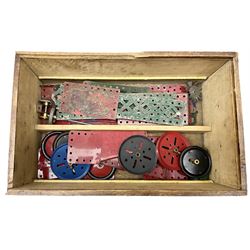 Meccano - wooden box with Set No.5 label to sliding lid, containing two lift-out trays and bottom layer of predominantly red and green sections, wheels, pulleys, rods, tyres etc, carrying handles to either end, L36cm D22.5cm H13.5cm